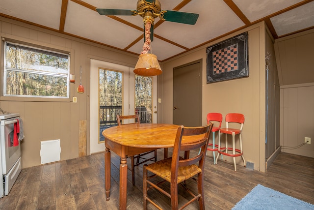 dining room with dark hardwood / wood-style flooring, wooden walls, and ceiling fan