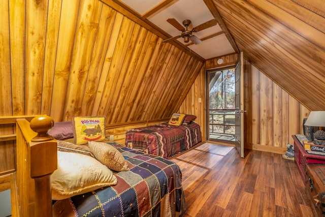 bedroom featuring access to outside, lofted ceiling, hardwood / wood-style floors, wood walls, and ceiling fan