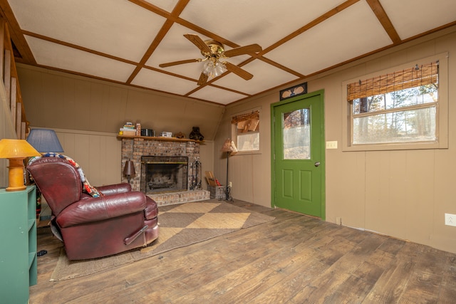 living room featuring wood-type flooring, wooden walls, coffered ceiling, ceiling fan, and a fireplace