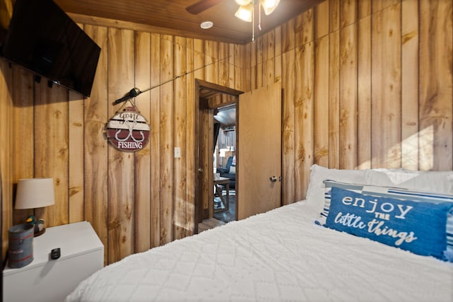 bedroom with ceiling fan and wooden walls