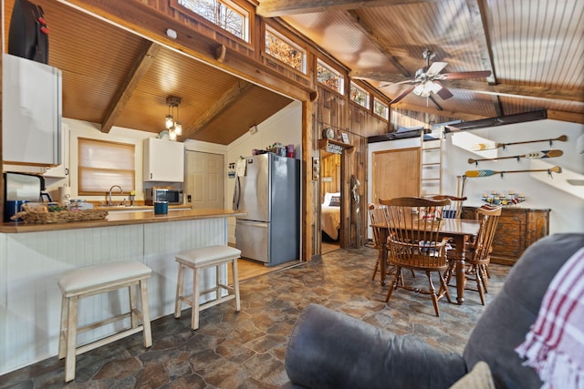 kitchen with wooden ceiling, lofted ceiling with beams, kitchen peninsula, white cabinetry, and stainless steel appliances