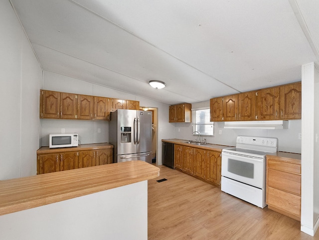 kitchen featuring lofted ceiling, range, sink, light hardwood / wood-style flooring, and stainless steel fridge