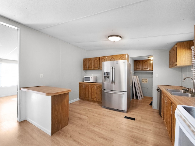 kitchen featuring white appliances, sink, light hardwood / wood-style flooring, and vaulted ceiling