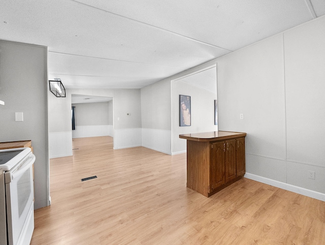 kitchen featuring white electric stove, kitchen peninsula, a textured ceiling, and light hardwood / wood-style flooring