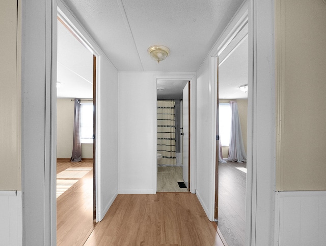 hall featuring a textured ceiling and light wood-type flooring