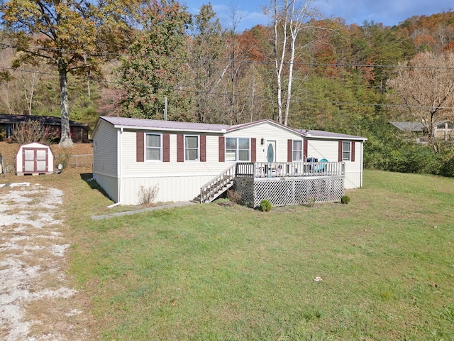 manufactured / mobile home with a front yard, a storage unit, and a wooden deck