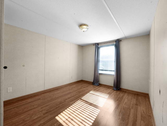 unfurnished room with a textured ceiling and hardwood / wood-style flooring