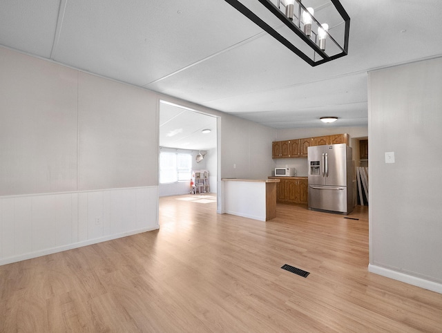 kitchen with light wood-type flooring and stainless steel fridge with ice dispenser