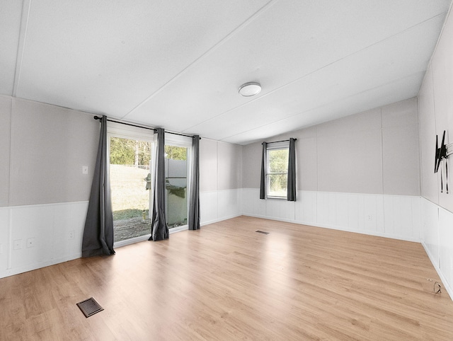 empty room featuring light wood-type flooring and vaulted ceiling