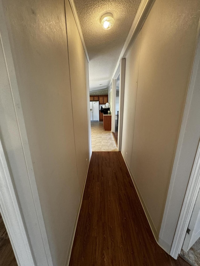 hallway with a textured ceiling, hardwood / wood-style flooring, and ornamental molding