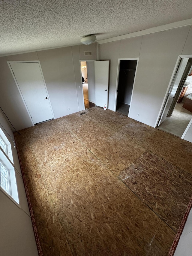 unfurnished bedroom with a walk in closet, a textured ceiling, and a closet