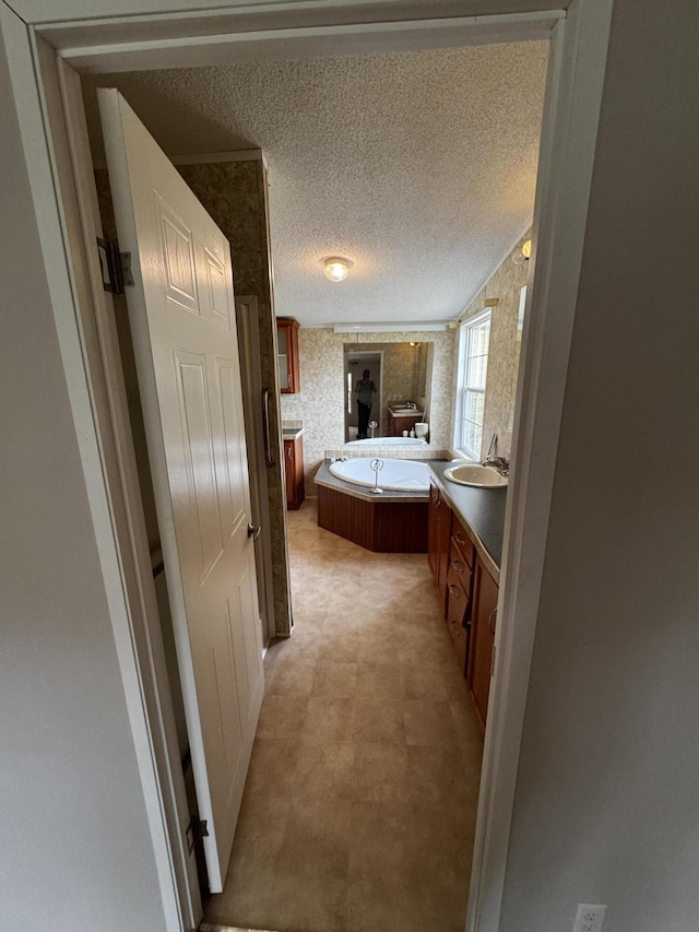 bathroom featuring a textured ceiling, vanity, and a bath