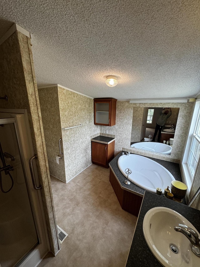 bathroom with a textured ceiling, independent shower and bath, and sink