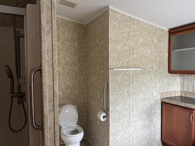 bathroom featuring a textured ceiling, toilet, ornamental molding, and a shower with door