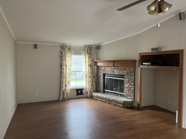 unfurnished living room with a textured ceiling, a stone fireplace, crown molding, and dark hardwood / wood-style floors