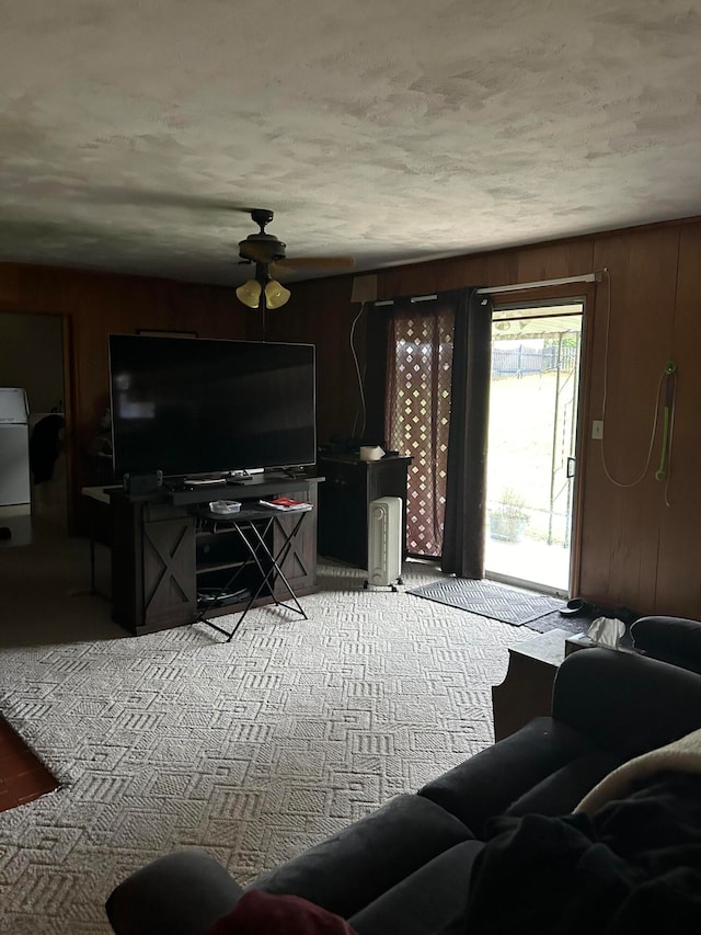 living room with ceiling fan, wooden walls, and carpet floors