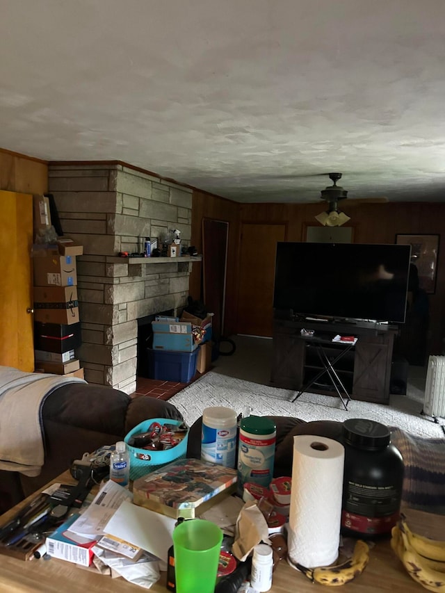 living room with a fireplace, ceiling fan, and wooden walls