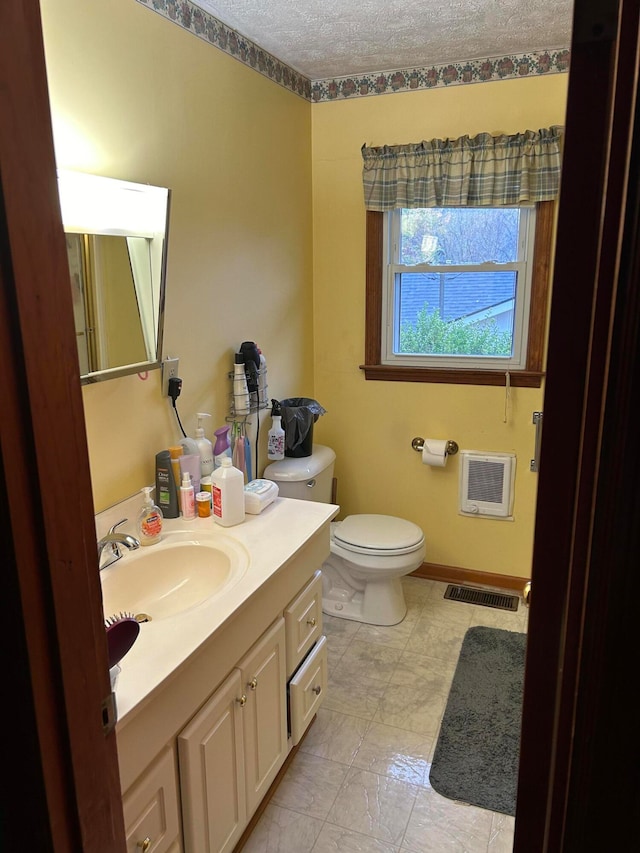 bathroom featuring vanity, a textured ceiling, heating unit, and toilet