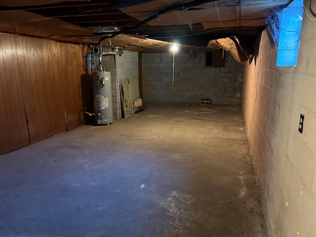 basement featuring water heater and wooden walls