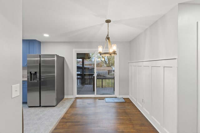 unfurnished dining area featuring hardwood / wood-style flooring and an inviting chandelier