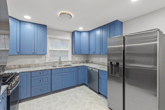 kitchen with blue cabinetry, light stone counters, sink, and appliances with stainless steel finishes