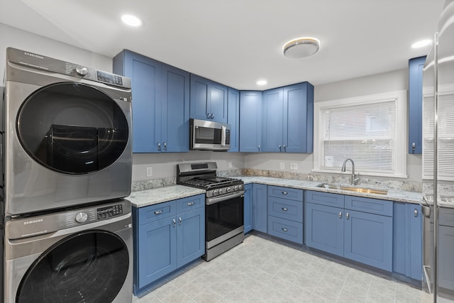 kitchen featuring light stone countertops, stainless steel appliances, blue cabinets, sink, and stacked washer / dryer