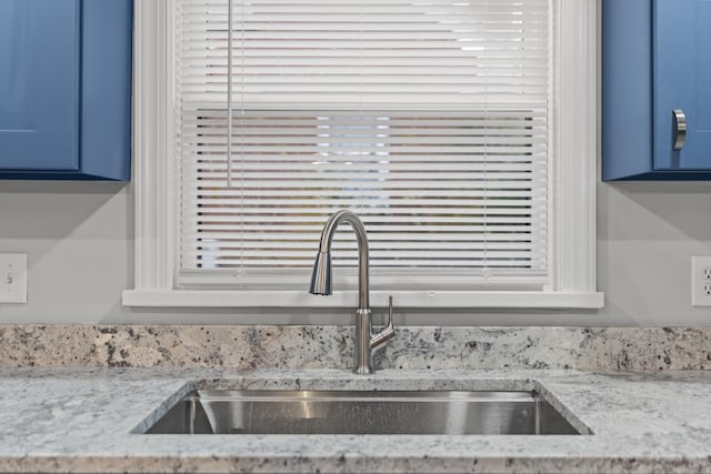 details featuring blue cabinetry, light stone countertops, and sink