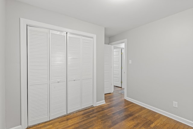 unfurnished bedroom with a closet and dark wood-type flooring