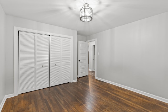 unfurnished bedroom with dark hardwood / wood-style flooring and a closet