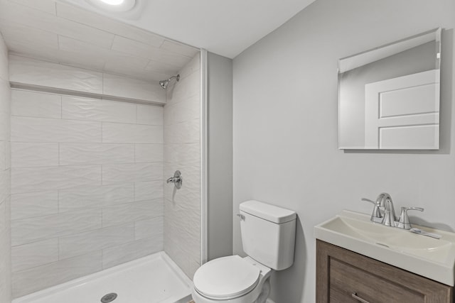 bathroom with vanity, toilet, and a tile shower