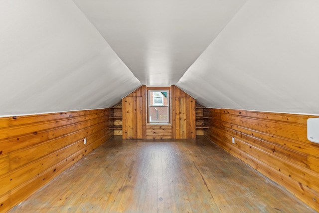 additional living space with hardwood / wood-style flooring, lofted ceiling, and wood walls