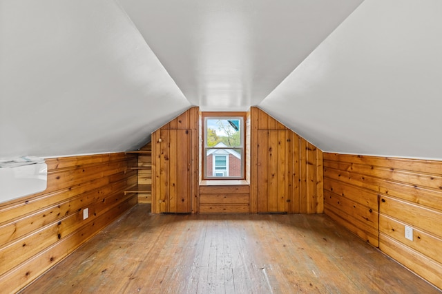 additional living space featuring wood-type flooring, vaulted ceiling, and wooden walls