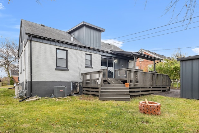 rear view of property featuring cooling unit, a lawn, an outdoor fire pit, and a wooden deck