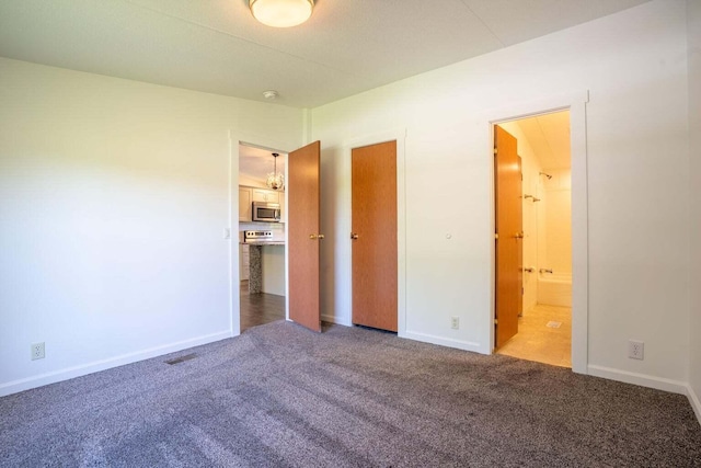 unfurnished bedroom featuring ensuite bathroom and carpet floors