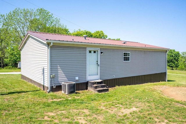 rear view of house featuring central AC unit and a yard