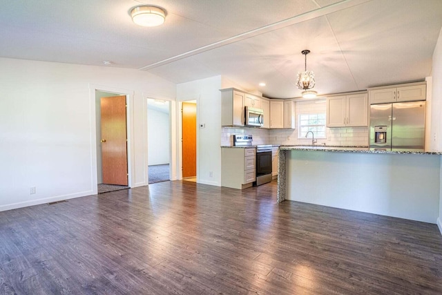 kitchen with dark wood-type flooring, light stone counters, backsplash, and appliances with stainless steel finishes