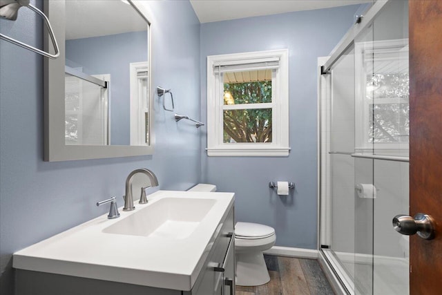 bathroom featuring vanity, toilet, a shower with shower door, and hardwood / wood-style floors