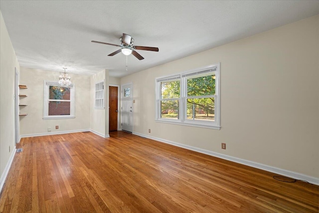 unfurnished room featuring ceiling fan with notable chandelier, a textured ceiling, and light hardwood / wood-style flooring