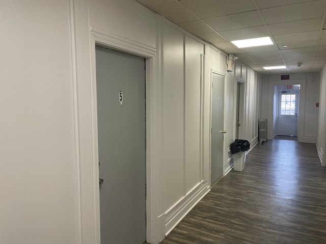 hall featuring radiator heating unit, dark hardwood / wood-style flooring, and a drop ceiling