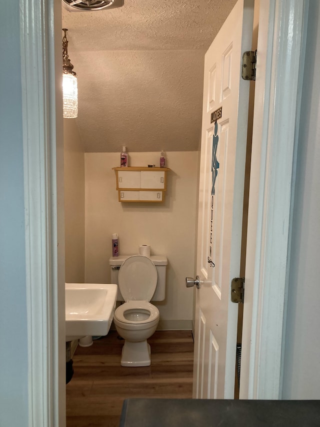 bathroom featuring toilet, sink, wood-type flooring, and a textured ceiling