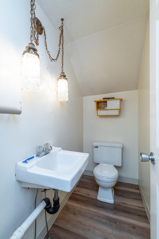 bathroom with sink, wood-type flooring, vaulted ceiling, and toilet