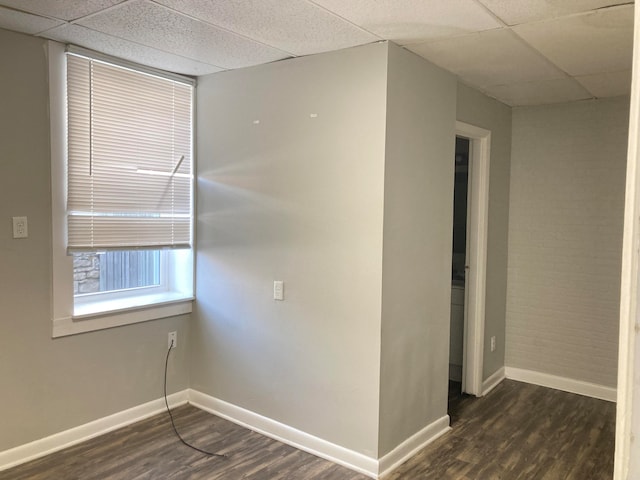 spare room with a paneled ceiling and dark hardwood / wood-style flooring