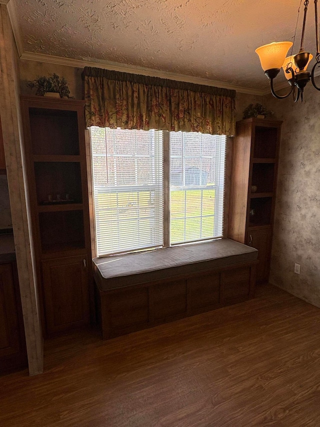 unfurnished dining area with a textured ceiling, ornamental molding, dark hardwood / wood-style floors, and an inviting chandelier