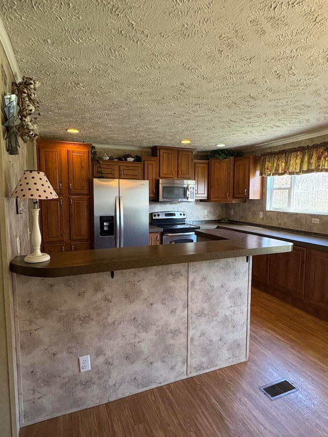 kitchen with hardwood / wood-style floors, a textured ceiling, and appliances with stainless steel finishes