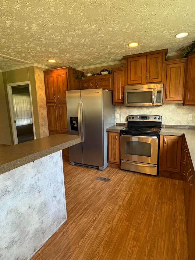 kitchen featuring a textured ceiling, tasteful backsplash, hardwood / wood-style floors, and stainless steel appliances