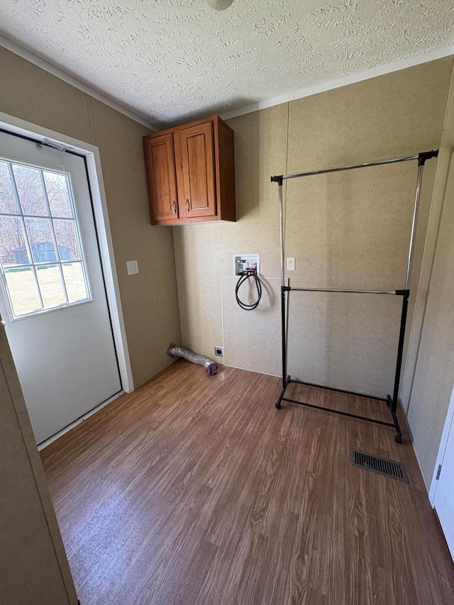 laundry area featuring cabinets, hardwood / wood-style flooring, washer hookup, a textured ceiling, and electric dryer hookup