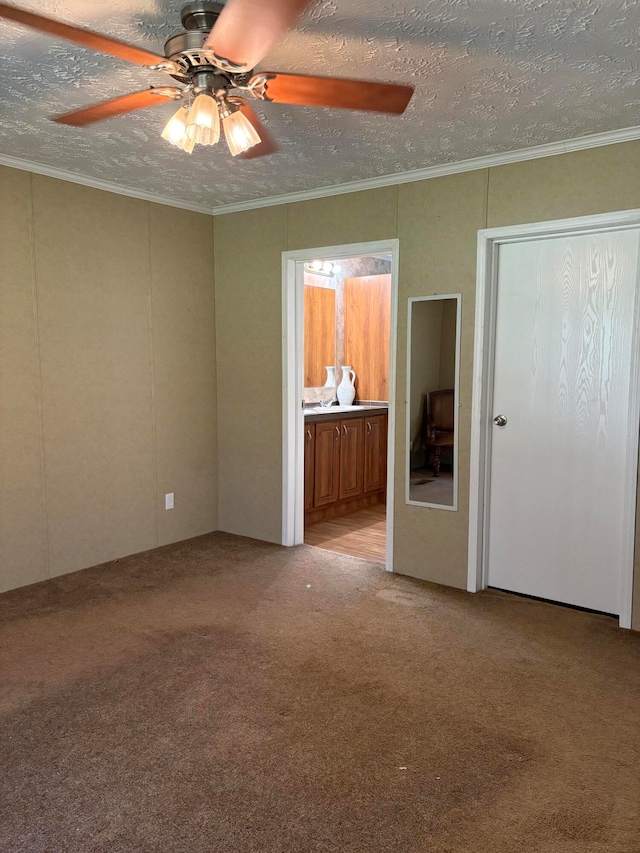 carpeted spare room with ceiling fan, a textured ceiling, and crown molding