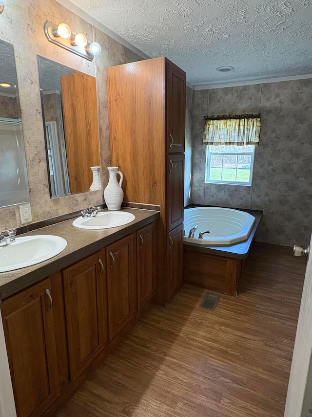 bathroom featuring a textured ceiling, vanity, hardwood / wood-style flooring, and a tub