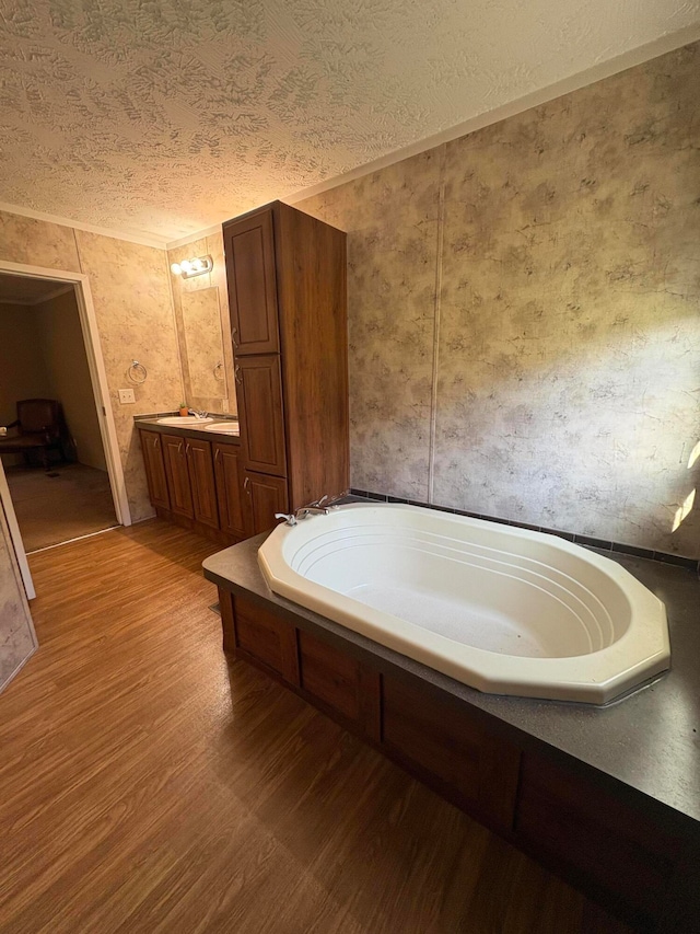 bathroom with a textured ceiling, a bath, hardwood / wood-style flooring, and vanity