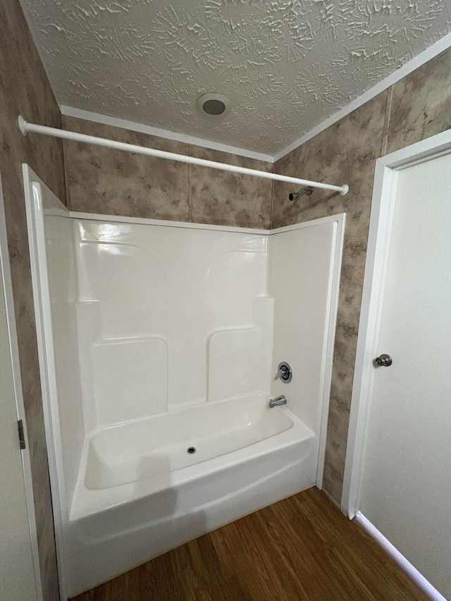 bathroom featuring tub / shower combination, wood-type flooring, and a textured ceiling